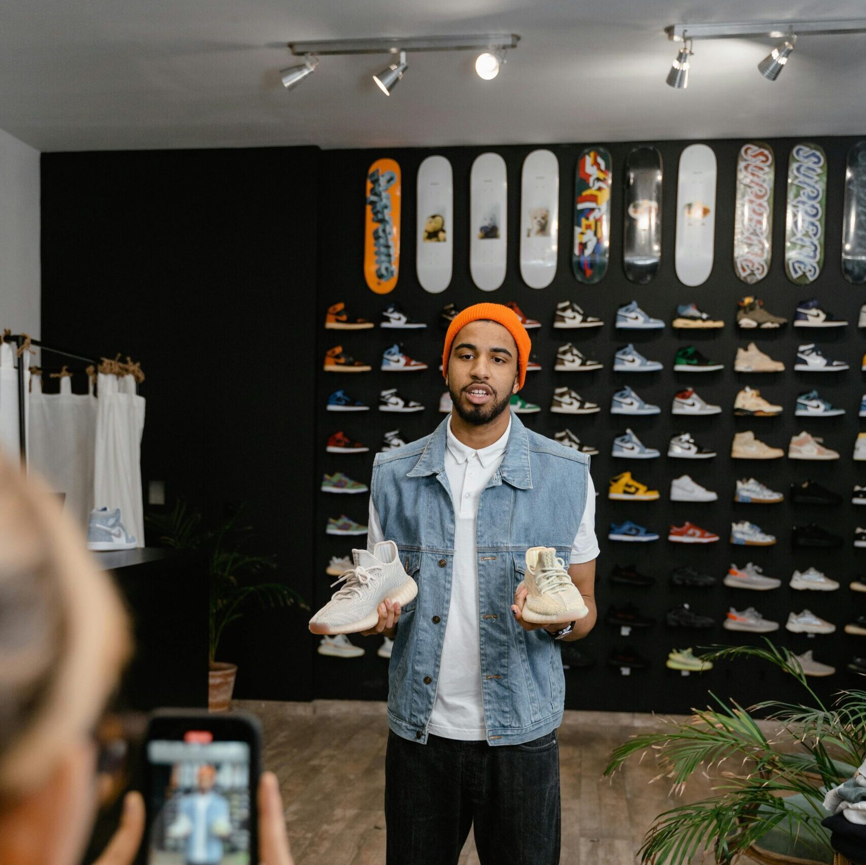 A man demonstrates shoes for an online promotional video in a boutique shop setting.
